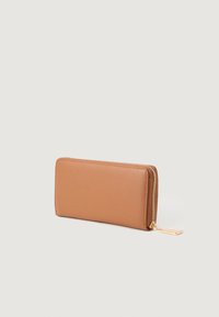 Portofel maro din piele artificială cu fermoar, cu o textură netedă, formă rectangulară și accesorii aurii, având un accent de etichetă mică.