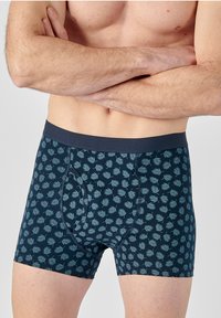 Pantaloni boxer di colore blu scuro con un motivo a foglia blu chiaro ripetuto, dotati di una comoda cintura elastica e di un design aderente.