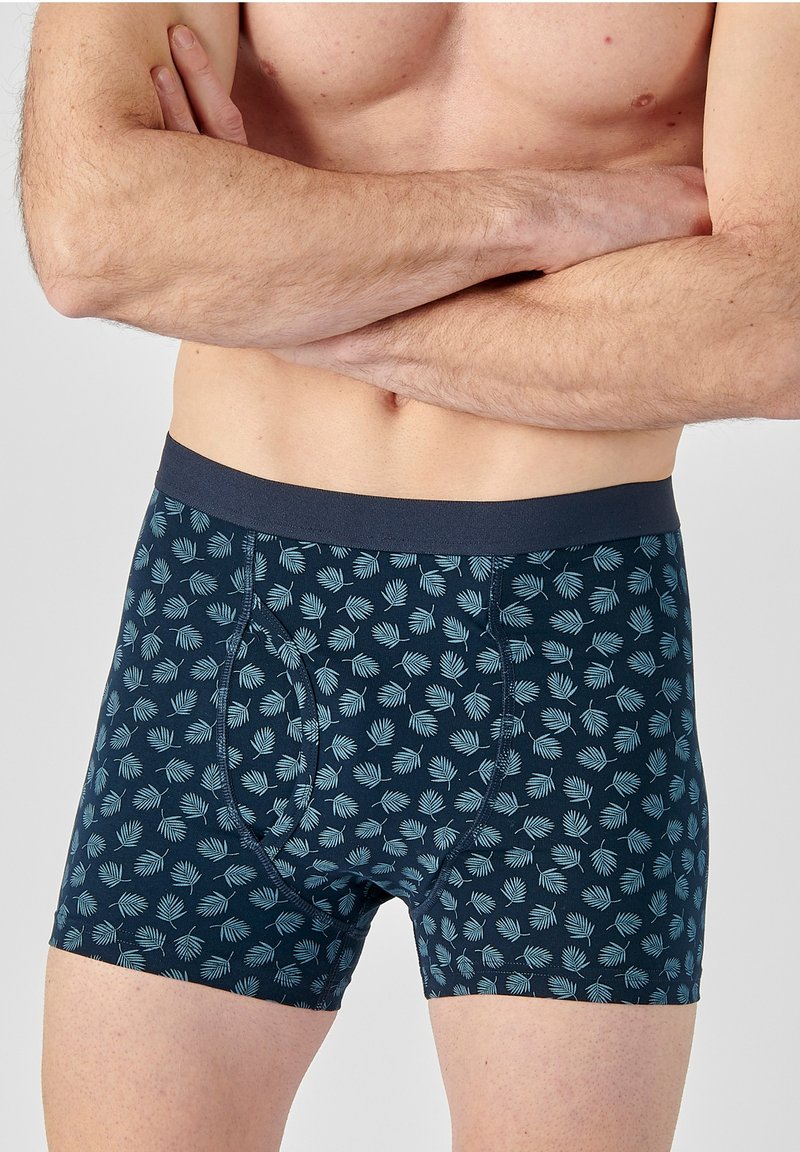 Pantaloni boxer di colore blu scuro con un motivo a foglia blu chiaro ripetuto, dotati di una comoda cintura elastica e di un design aderente.