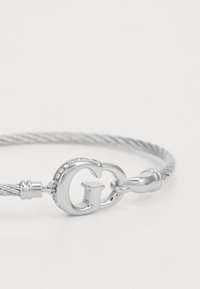 Bracciale in argento con un design a filo attorcigliato, dotato di una chiusura con il logo GG prominente, accentuata da piccole pietre trasparenti.