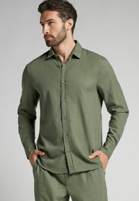 Groene langemouwen shirt gemaakt van textuurstof, met een knoopsluiting, opstaande kraag en slim fit. Accenten omvatten bijpassende knopen.