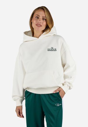 White hooded sweatshirt with front pocket and logo text. Soft fabric, relaxed fit, ribbed cuffs and hem. Paired with dark green athletic pants.