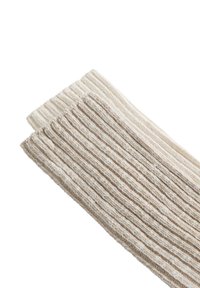 Két bézs és krémszínű bordázott kötött zokni párhuzamosan egymás mellett fehér háttéren.