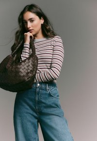Brown woven handbag, striped long-sleeve shirt in muted colors, high-waisted light denim jeans. Smooth textures, casual fit.