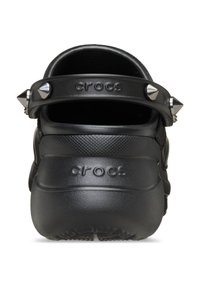 Des Crocs noirs avec une finition texturée, dotés d'une sangle ornée de clous et d'un logo en relief. La vue arrière met en avant la forme et le design distincts.