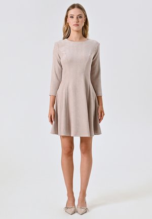 Robe beige à manches trois-quarts avec un corsage ajusté et une jupe évasée. Tissu doux et texturé avec un col rond. Ourlet court.