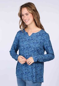 Blaue Langarmbluse mit floralem Muster, V-Ausschnitt und strukturiertem Stoff. Hauttöne und Haare werden nicht beschrieben.