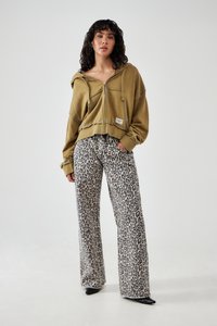 Olivovo zelená skrátená mikina s .zipsom a šnúrkami; spárovaná s nohavicami so širokými nohavicami a leopardím vzorom. Čierne ihlové topánky dotvárajú celkový look.