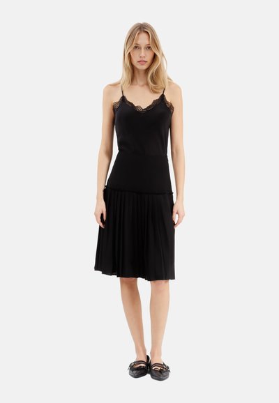 Abito nero con spalline sottili regolabili, dettagli in pizzo sullo scollo, corpetto aderente e gonna plissettata. Tessuto dalla texture liscia.