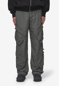 Cargo pants in a dull olive green color, made from lightweight material. Features multiple large pockets and zippers on the sides.
