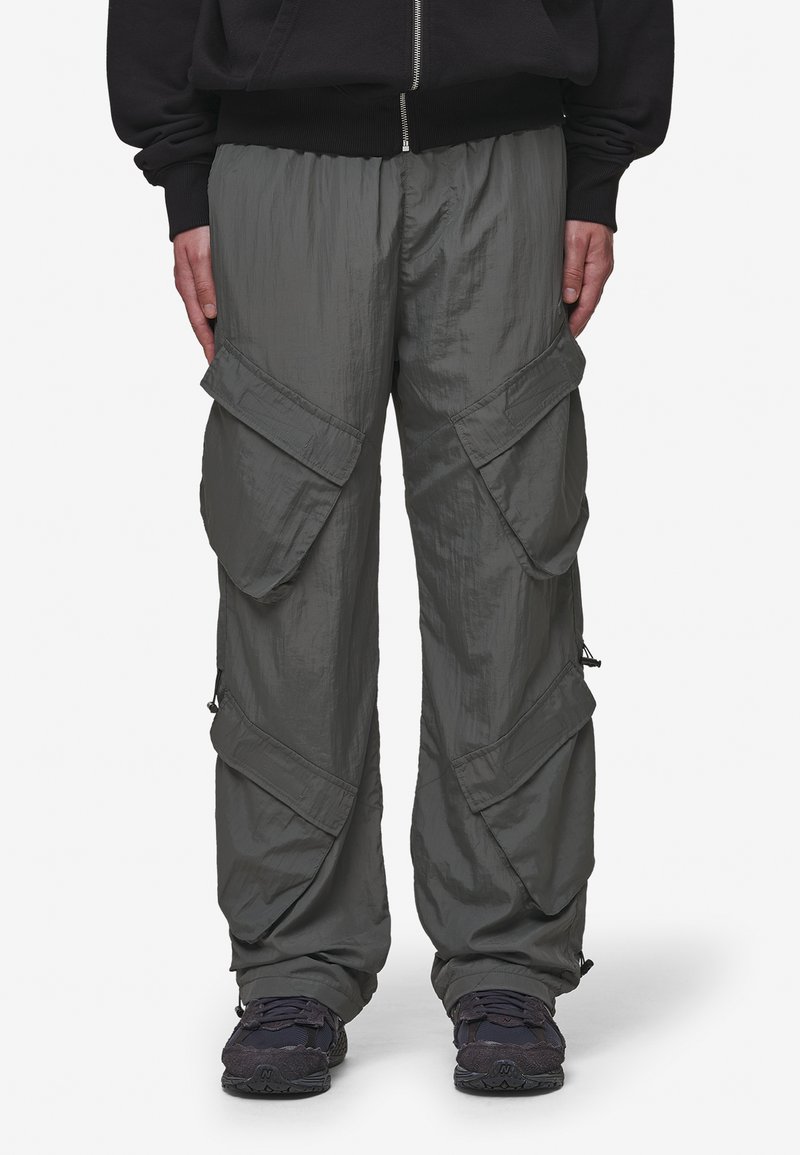 Cargo pants in a dull olive green color, made from lightweight material. Features multiple large pockets and zippers on the sides.