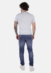 Maglione corto azzurro a maniche corte in cotone, abbinato a jeans in denim blu. Caratterizzato da un design aderente e orlo a coste semplice. Sneakers bianche completano l'outfit.