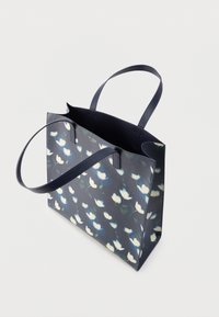 Sac fourre-tout floral bleu avec deux longues anses, fabriqué en matériau texturé ; présente des motifs de fleurs blanches et bleu clair sur un fond sombre.