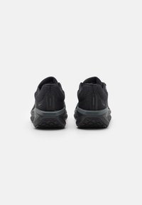 Des chaussures de sport noires avec des tiges en maille, des semelles rembourrées et un dos texturé. Elles présentent un design épuré et des semelles extérieures en caoutchouc pour une meilleure adhérence.