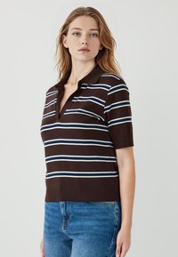 Bruin en wit gestreepte polo met korte mouwen en een kraag, met een fitted ontwerp en subtiele ribbelstructuur aan de zoom.