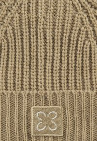 Gebreide beanie in tan met geribbelde textuur. Kenmerkt zich door een zachte wolmix, een vierkant embleem met een decoratieve logo gestikt in crème.