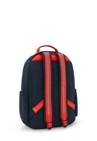 Námornícký batoh s červenými akcenty, prošívanou texturou, polstrovanými nastavitelnými popruhy, bočními kapsami a horním úchopem. Moderní design s zaobleným tvarem.