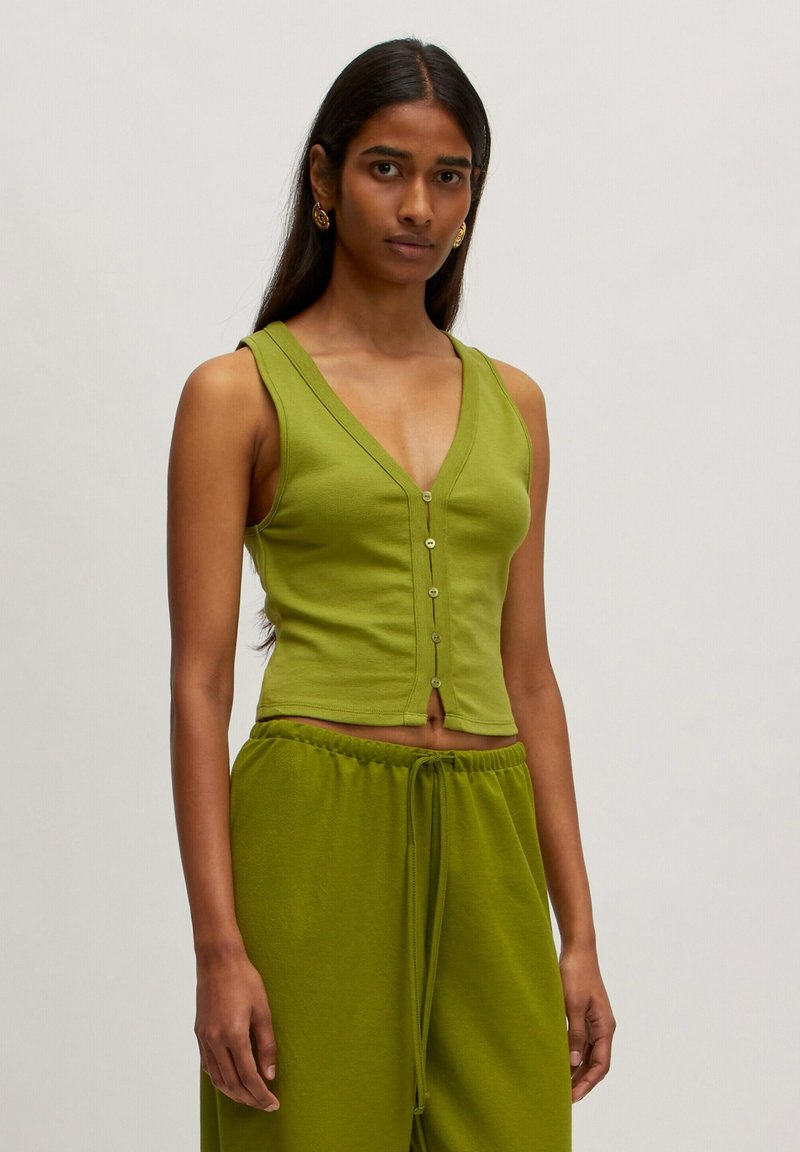 Grüner ärmelloser Oberteil mit tiefem V-Ausschnitt, der fünf kleine Knöpfe auf der Vorderseite hat und einen cropped Schnitt aufweist, aus weichem Material gefertigt.