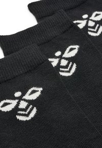 Schwarze Baumwollsocken mit weißem Bienenlogo-Design, ausgestattet mit gerippten Bündchen und einem glatten, strukturierten Muster im gesamten Stoff.