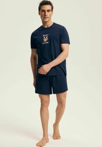 Granatowa bawełniana koszulka z grafiką "ENJOY NATURE" oraz dopasowanymi szortami. Prosty design i luźny krój. Boso na neutralnym tle.