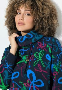 Sudadera navy con patrones de lazo coloridos en rosa, verde y azul. Presenta un cuello alto y cordón con herrajes dorados. Textura suave.
