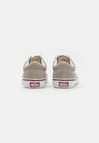 Beige semskinn-sneakers med hvite detaljer, med en flat gummisåle og omvendt logo på hælen. Lave sko med enkle sømdetaljer.