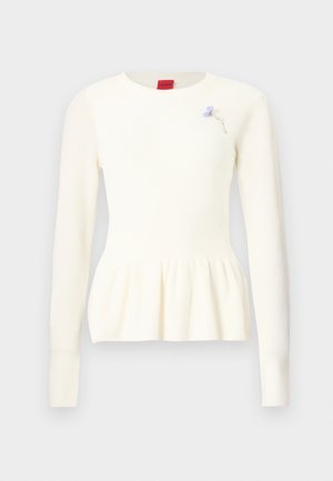 Witte gebreide trui met lange mouwen, ronde hals, peplum zoom en een klein blauw bloemenaccentspeldje op de borst.