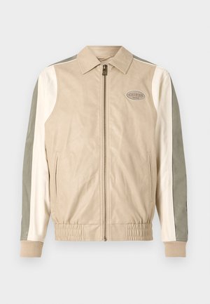 Beige Leder-Bomberjacke mit grünen und weißen Paneelen, Reißverschluss, gerippten Bündchen und GUESS-Logo-Patch auf der Brust.