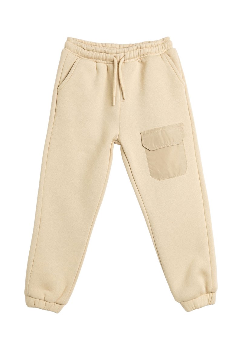Pantalones de chándal beige hechos de material suave, con cintura elástica, bolsillos laterales y un bolsillo de parche en la pierna derecha.