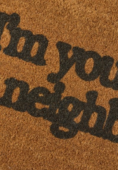 Dørmåtte af kokosfibre med sort tekst, der siger "Jeg er din nabo" på en brun baggrund af naturlige fibre.
