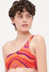 Μπικίνι τοπ με έναν ώμο σε έντονο πορτοκαλί, ροζ και μωβ κυματιστό σχέδιο. Διαθέτει υφή υφάσματος και μινιμαλιστικό σχέδιο χωρίς μεταλλικά στοιχεία.