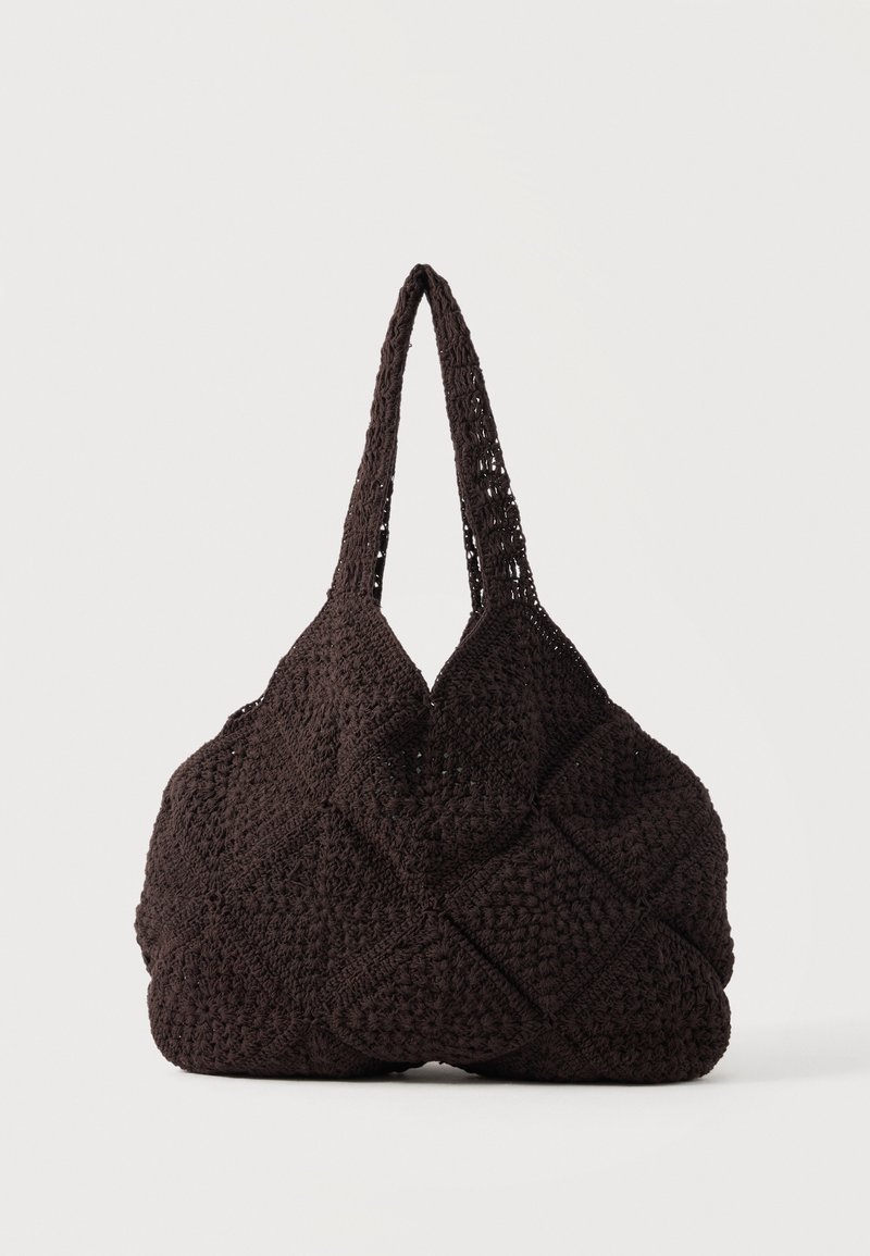 Sac cabas noir au crochet avec motifs carrés texturés et deux bretelles, posé sur un fond uni.
