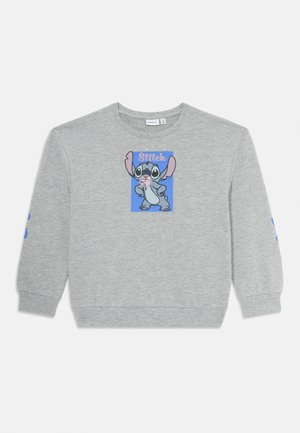 Bluză gri pentru copii cu mâneci lungi, având un personaj de desene animate zâmbitor Stitch într-un dreptunghi albastru și cuvântul „Stitch” deasupra.