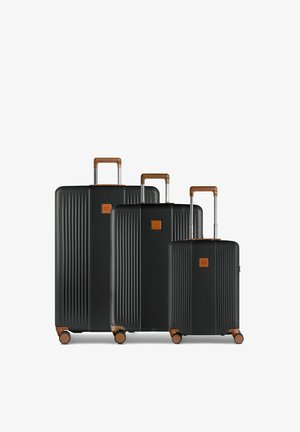 Drei schwarze Hartschalenkoffer mit braunen Griffen und je vier Rädern, von größtem bis kleinstem in einer Reihe angeordnet.