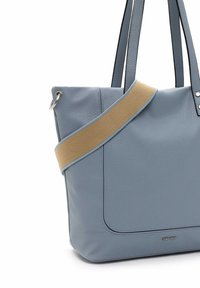 Sac fourre-tout en cuir bleu avec une sangle en tissu beige, doté d'une texture lisse, d'un grand compartiment principal et d'accents en métal argenté.