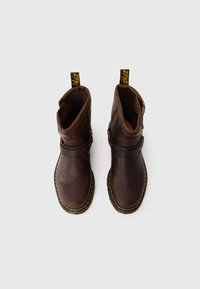 Bottines en cuir marron avec un bout rond, des détails de boucle sur le côté, des coutures jaunes et des languettes pour un enfilage facile.