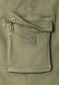 Zelen žep iz tkanine z oznako "Pepe Jeans London." Ima zapiralo na pritisk, robovi so šivani, kar povečuje trpežnost in dizajn.