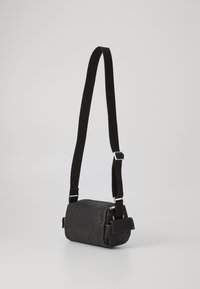Borsa in pelle nera dalla forma rettangolare, con tracolla in tessuto regolabile, finiture in metallo argentato e chiusura a zip. Texture liscia.