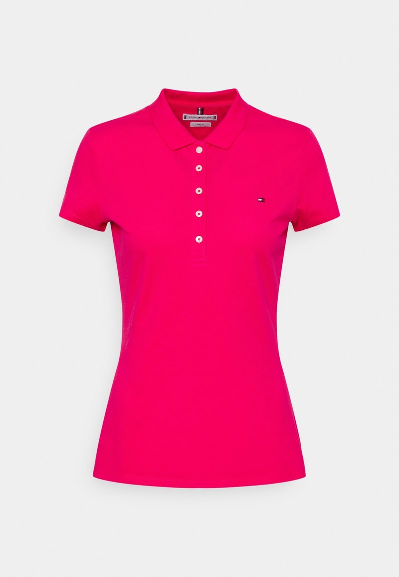 Polo rose en coton avec un col classique, des manches courtes, une rangée de boutons et un petit logo sur le côté gauche de la poitrine. Texture lisse.
