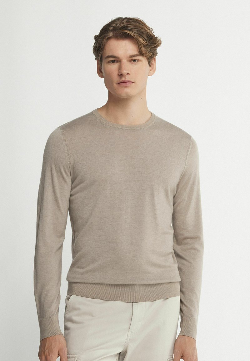 Beige långärmad tröja med rund halsringning, tillverkad av ett mjukt material. Har ribbade muddar och nederkant. Slät textur genom hela plagget.