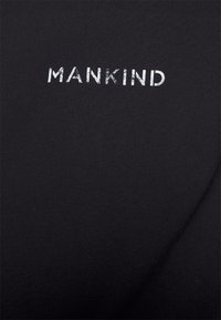 Hvid, slidt tekst "MANKIND" på sort stof, centreret og med store bogstaver.