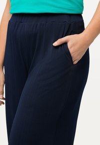 Námořnické modré, ribbed sportovní kalhoty s uvolněným střihem a elastickým pasem. Obsahují boční kapsy a hladkou texturu.