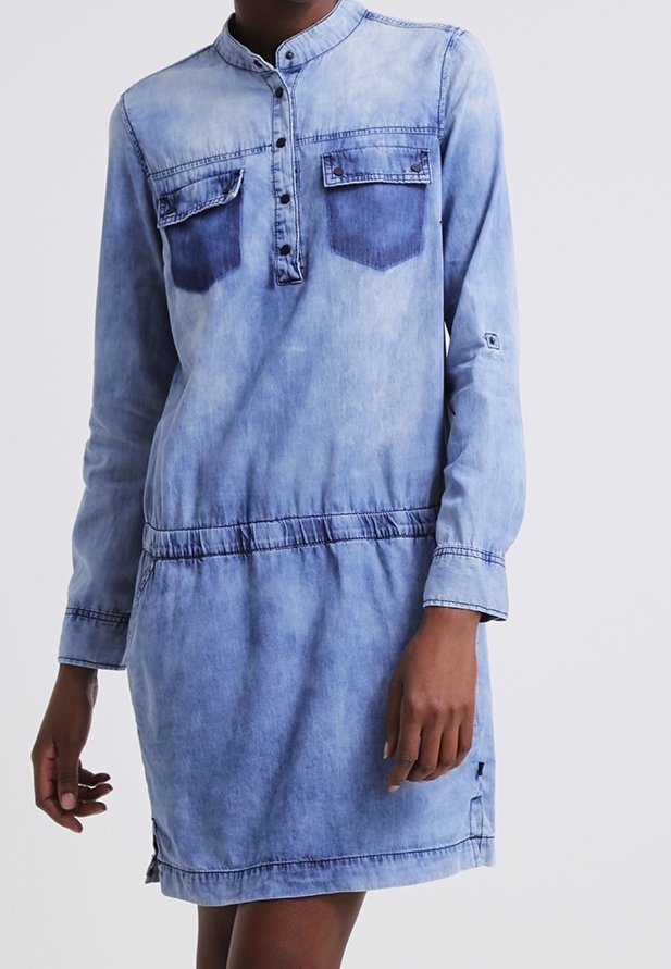 Robe en denim bleu clair, manches longues, col style henley, deux poches poitrine, taille élastique et détail d'ourlet effiloché.