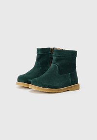 Botines de ante verde con una suela de goma marrón, presentan un cierre lateral y un detalle de costura en contraste. Textura suave con punta redondeada.