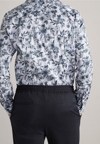Kwiatowa koszula z długim rękawem w niebiesko-szary wzór; czarne spodnie z elastycznym pasem, z dwiema tylnymi kieszeniami i detalem logo.
