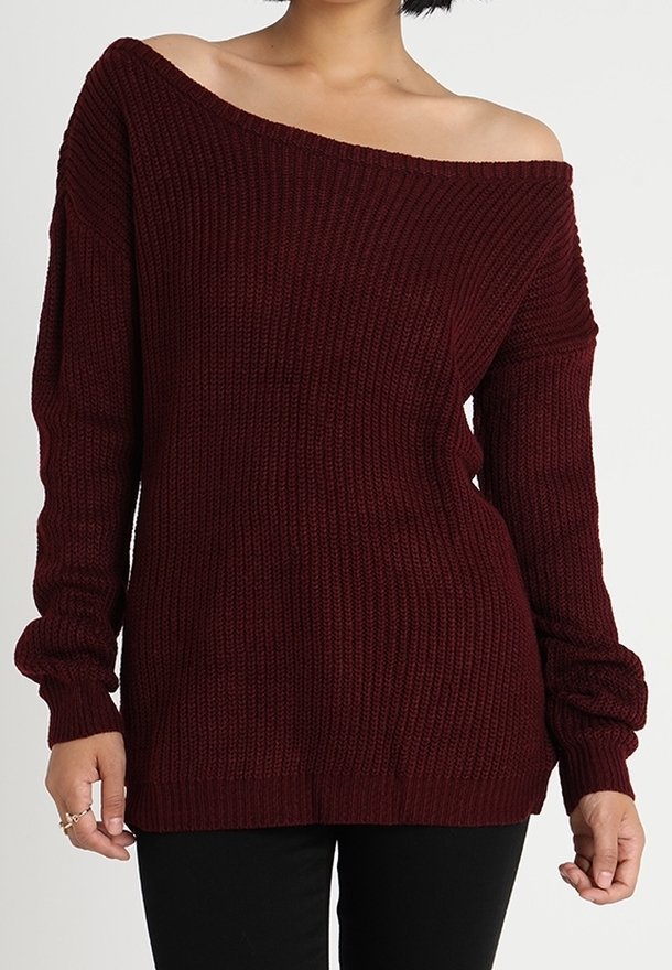 Pull en tricot bordeaux à épaules dénudées, avec des manches longues, texture côtelée et coupe décontractée. L'ourlet tombe en dessous de la taille.
