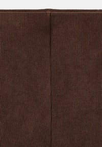Brown ribbed fabric with a soft texture, featuring a vertical stripe pattern. The material is stretchy and form-fitting.