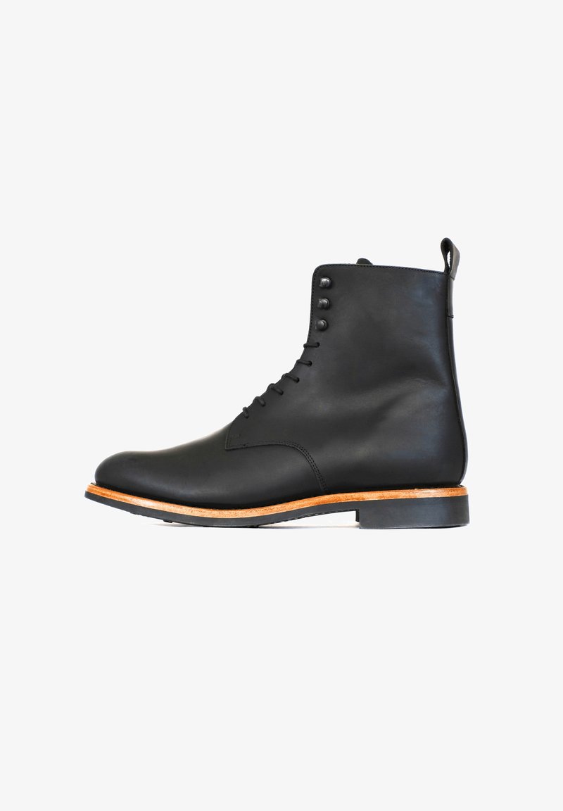 Stivale alla caviglia in pelle nera con finitura liscia, punta rotonda, chiusura con lacci e quattro occhielli in metallo. Presenta una suola intermedia in legno marrone chiaro e suola in gomma.