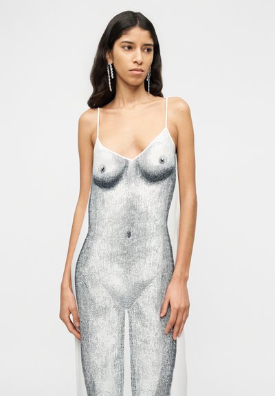 Αμάνικο, εφαρμοστό φόρεμα σε λευκό με γραφικό μοτίβο σε τόνους του γκρι που μοιάζει με κορμό. Διαθέτει λεπτές τιράντες στους ώμους και πλευρικές σχισμές.