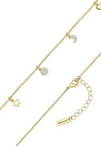 Zelta tonis apro jaukām detalēm – zvaigznēm, pusmēnesim un apaļām piekariņām, rotātām ar caurspīdīgiem kristāliem. Aproce ir pabeigta ar omā piedziņu un pagarināšanas ķēdi.